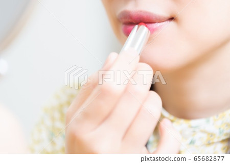 Woman applying lipstick and applying makeup Woman applying lipstick and applying makeup 65682877