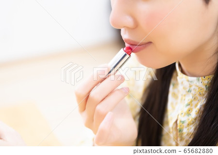 Woman applying lipstick and applying makeup Woman applying lipstick and applying makeup 65682880