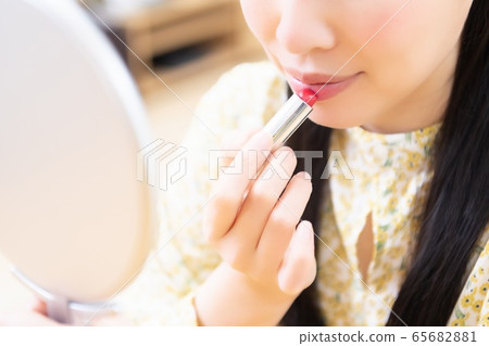 Woman applying lipstick and applying makeup Woman applying lipstick and applying makeup 65682881