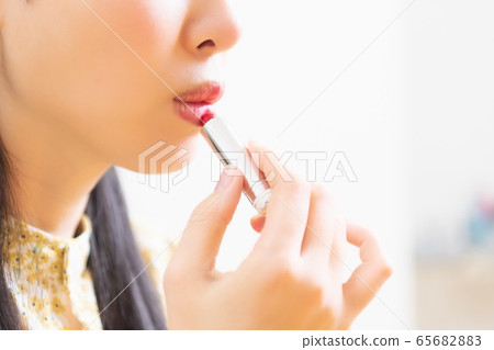 Woman applying lipstick and applying makeup Woman applying lipstick and applying makeup 65682883