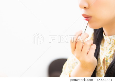 Woman applying lipstick and applying makeup Woman applying lipstick and applying makeup 65682884