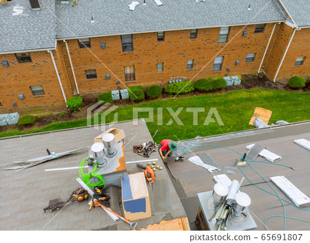 Roofer working on replacement asphalt shingle roof 65691807