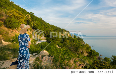 The female traveler is happy and relaxed on the hill with a beautiful sea view. 65694351