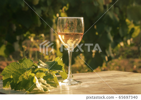 glass with white wine in vineyard on old table 65697340