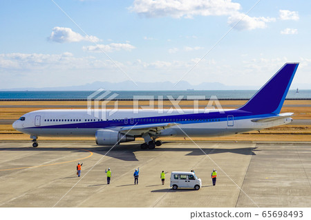Airport clerk waving on an airplane and looking off 65698493