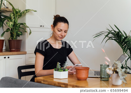 Millennial girl working from home in a plant room. Freelance florist, young business owner, home Millennial girl working from home in a plant room. Freelance florist, young business owner, home 65699494