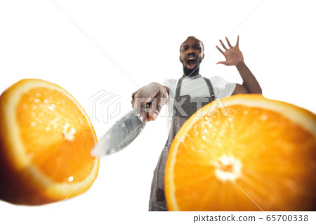 Amazing african-american man preparing unbelievable food with close up action, details and bright emotions, professional cook. Cutting orange on the fly Amazing african-american man preparing unbelievable food with close up action, details and bright emotions, professional cook. Cutting orange on the fly 65700338