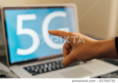 Blue background with 5G sign on laptop and person working. Fast mobile network. Evolution in Blue background with 5G sign on laptop and person working. Fast mobile network. Evolution in 65700730
