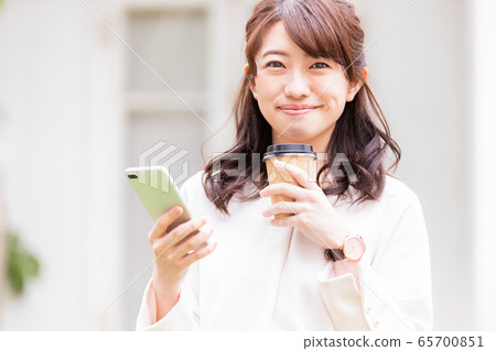 年輕女子智能手機外賣杯在戶外 年輕女子智能手機外賣杯在戶外 65700851