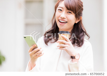 年輕女子智能手機外賣杯在戶外 年輕女子智能手機外賣杯在戶外 65700852