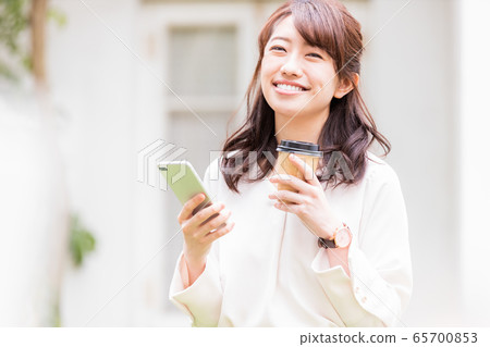 年輕女子智能手機外賣杯在戶外 年輕女子智能手機外賣杯在戶外 65700853