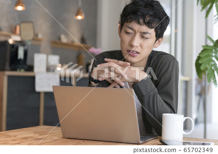 A man frowning in front of a laptop A man frowning in front of a laptop 65702349