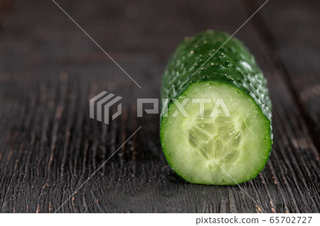 Closeup on cucumber piece on the dark wooden table Closeup on cucumber piece on the dark wooden table 65702727
