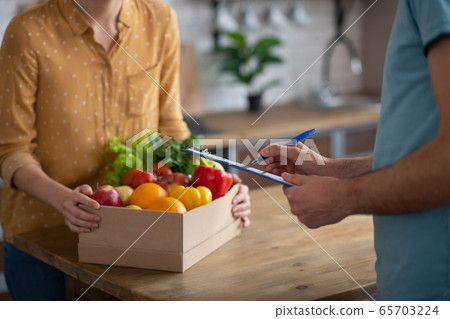 Woman receiving home groceries delivery from a courrier 65703224