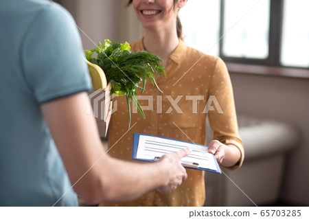 Dark-haired customer receiving groceries delivered by the courrier Dark-haired customer receiving groceries delivered by the courrier 65703285