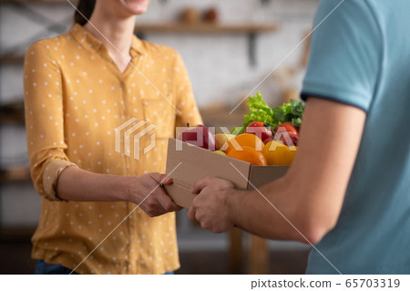 Close up picture of a woman receiving groceries from the courrier Close up picture of a woman receiving groceries from the courrier 65703319