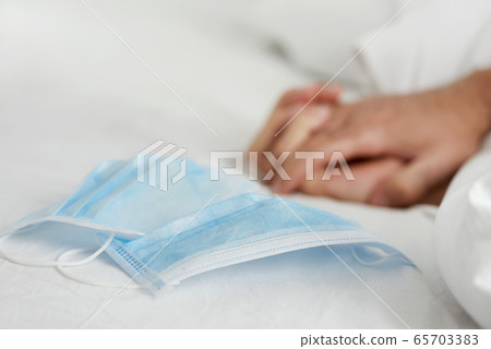 two people on bed next to two surgical masks two people on bed next to two surgical masks 65703383