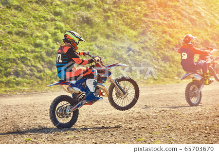 A team of mountain bike athletes starts, smoke and dust fly out from under the wheels off-road. Motocross outdoor activity concept. A team of mountain bike athletes starts, smoke and dust fly out from under the wheels off-road. Motocross outdoor activity concept. 65703670