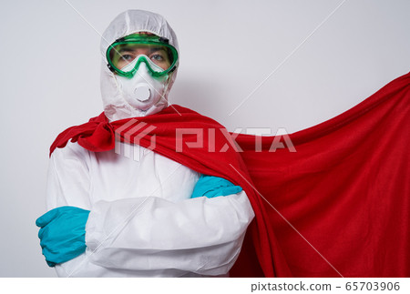 Doctor is wearing PPE - costume, gloves and surgical face mask in superhero cape. Doctor is wearing PPE - costume, gloves and surgical face mask in superhero cape. 65703906