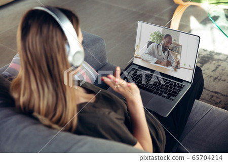 Young woman getting online medical help and advice during videocall with doctor checking symtoms aand explaining the drug's reciepes Young woman getting online medical help and advice during videocall with doctor checking symtoms aand explaining the drug's reciepes 65704214