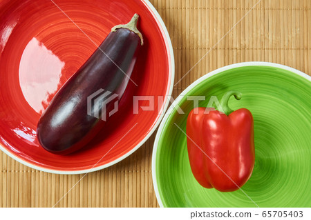 purple eggplant on a red plate and red bell pepper purple eggplant on a red plate and red bell pepper 65705403