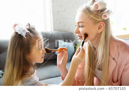 Mother and daughter, sisters have quite, beauty and fun day together at home. Comfort and togetherness. Do a make up, using cosmetics, masks, moisturizers, brushes and lipsticks 65707185