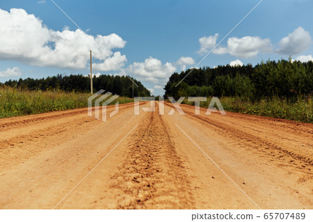 Sandy road surrounded by green forest in summer 65707489