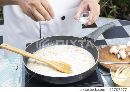 Chef putting salt in the pan for cooking mushroom 65707977