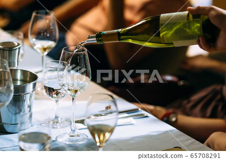 Waiter hand pouring wine in a glass served table Waiter hand pouring wine in a glass served table 65708291