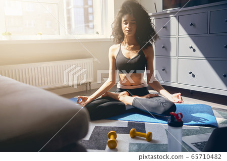 Relaxed young female doing meditation at home 65710482