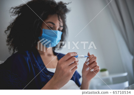 Close up of serious girl that looking at thermometer Close up of serious girl that looking at thermometer 65710534