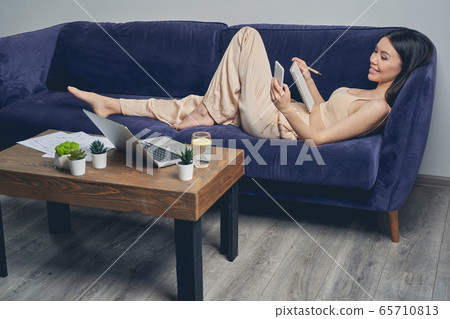 Cheerful young woman using smartphone at home Cheerful young woman using smartphone at home 65710813
