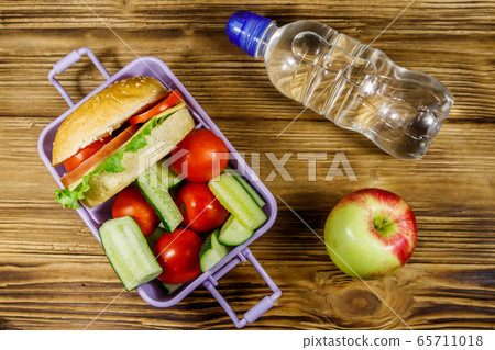 Bottle of water, apple and lunch box with burgers Bottle of water, apple and lunch box with burgers 65711018