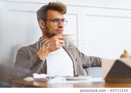Handsome young man drinking coffee in cafe 65711143