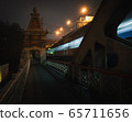 pedestrian railway bridge and lights of a passing train 65711656