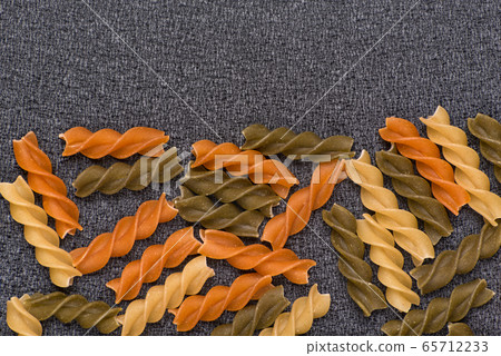 Fusilli multi-colored pasta on grey background. 65712233