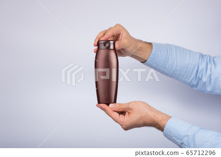 Brown bottle of shampoo or lotion in male hand on Brown bottle of shampoo or lotion in male hand on 65712296