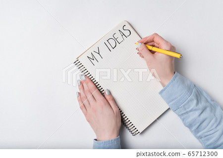 Female hands writing words MY IDEAS. Top view of Female hands writing words MY IDEAS. Top view of 65712300