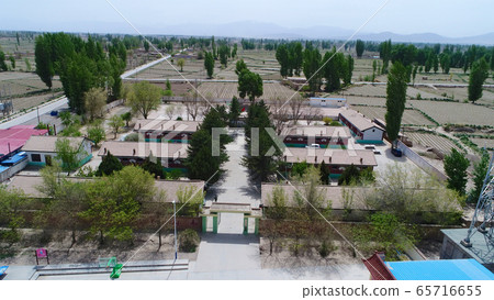 Aerial view of small poor village with school in the middle of dry farmland 65716655