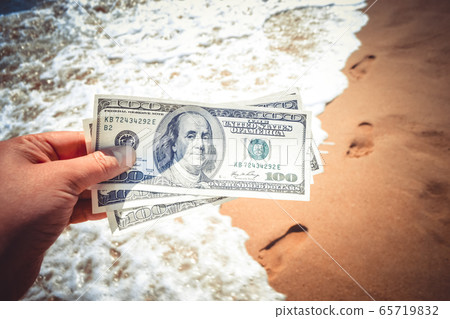 Girl holding money bill of 300 dollars on background of sea ocean Girl holding money bill of 300 dollars on background of sea ocean 65719832