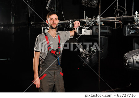 The lighting engineer adjusts the lights on stage behind the scenes The lighting engineer adjusts the lights on stage behind the scenes 65727716