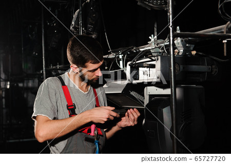The lighting engineer adjusts the lights on stage behind the scenes The lighting engineer adjusts the lights on stage behind the scenes 65727720