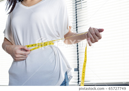 Woman with perfect waist with measuring tape. 65727749