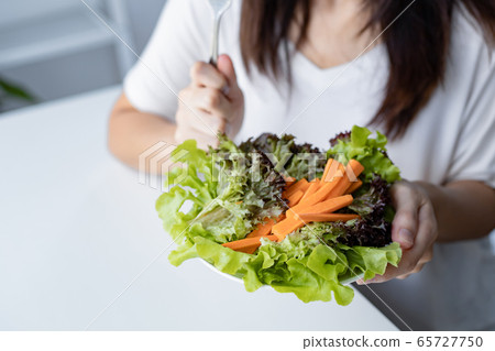 Young woman eating healthy salad in diet concept. 65727750