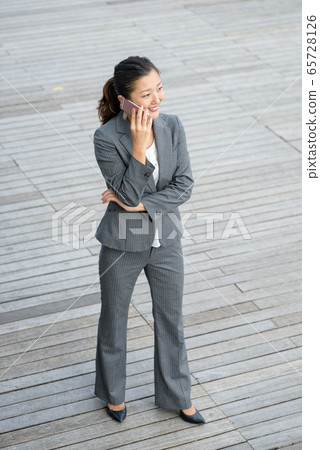 Businesswoman using smartphone outdoors 65728126