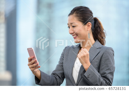 Businesswoman celebrate success while using smartphone outdoors Businesswoman celebrate success while using smartphone outdoors 65728131