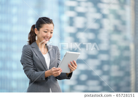 Successful businesswoman using iPad outdoors 65728151