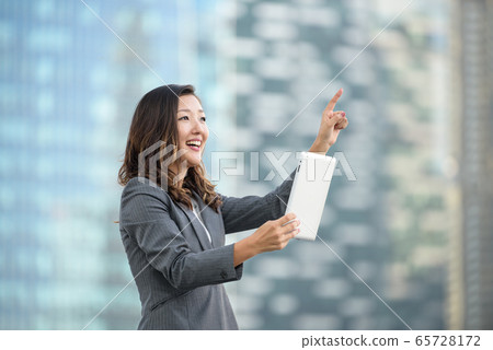 Successful businesswoman using iPad outdoors 65728172