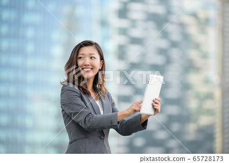 Successful businesswoman using iPad outdoors 65728173
