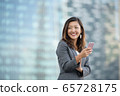 Successful businesswoman using smartphone outdoors 65728175